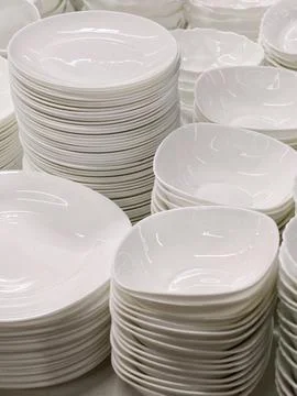 White ceramic kitchenware plates bowls and assorted items neatly stacked on.. Stockfoto's