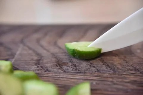 White ceramic knife cut a slice of a cucumber Stock Photos