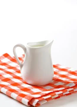 White ceramic milk pitcher on checkered cloth 스톡 사진