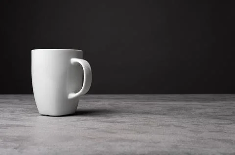 White Ceramic Mug on Grey Table with Dark Background Stock Photos