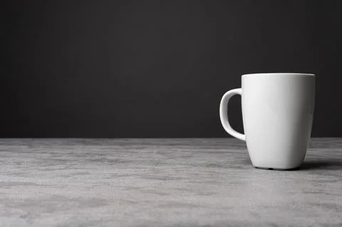 White Ceramic Mug on Grey Table with Dark Background Stock Photos