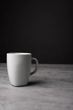 White Ceramic Mug on Grey Table with Dark Background Stock Photos