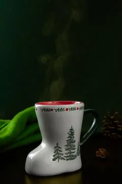 White ceramic mug shaped like a boot, featuring green fir tree illustrations Stock Photos