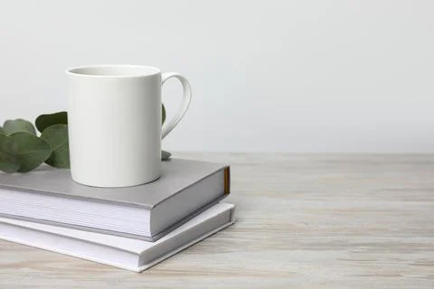 White ceramic mug, stack of books and eucalyptus branch on white wooden tab.. Stockfoto's
