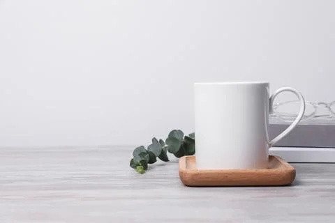 White ceramic mug, stack of books and eucalyptus branch on white wooden tab.. Stock Photos