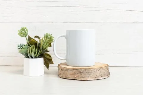 White ceramic mug on the table with a pot of flowers. Stock Photos