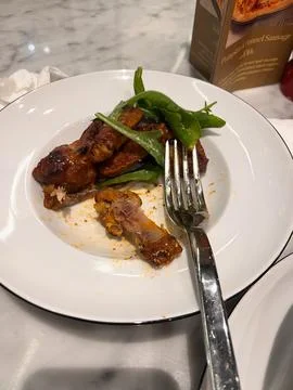 A white ceramic plate containing leftover roasted chicken wings Stock Photos
