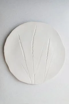 White ceramic plate with embossed wheat stalk pattern on light background Stock Photos