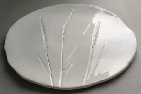White ceramic plate with embossed wheat pattern on gray background Stock Photos