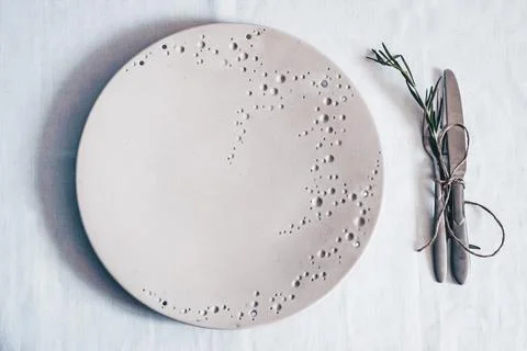 White ceramic plate with textured pattern and fork knife with rosemary on Stock Photos