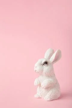 White ceramic rabbit on pink background. Vertical photo Stock Photos