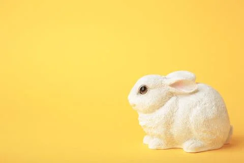 White ceramic rabbit on yellow background. Space for text Stock Photos