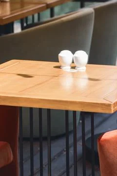 White ceramic salt and pepper shakers on wooden table in outdoor cafe Stock Photos