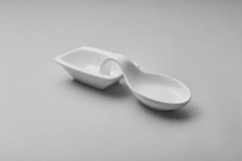 A white ceramic spoon rest sits on a light gray surface Foto stock