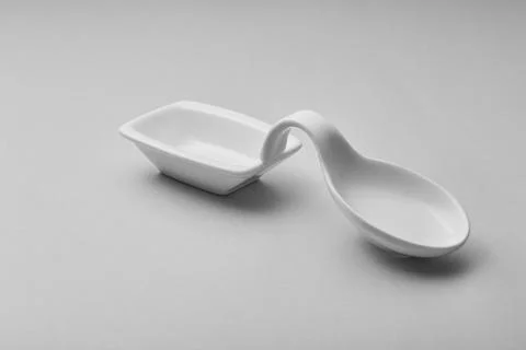 A white ceramic spoon rest sits on a light gray surface Foto stock