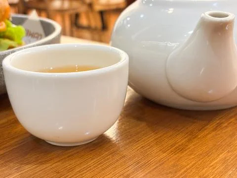 A white ceramic teacup filled with light amber tea Stock Photos