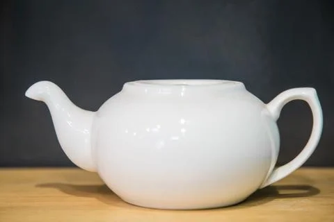 White ceramic teapot on a dark background. Stock Photos