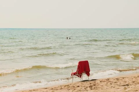 White chair with red cover standing at the summer beach in front of sea and c Stock Photos