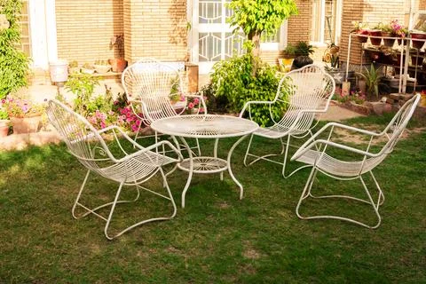 White Chairs and Table Set in a Vibrant Flower-Filled Garden Stock Photos