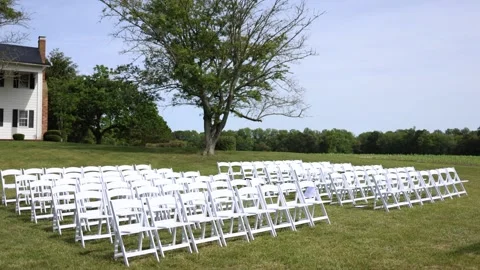 White chairs set up for an outdoor wedding ceremony Stock Footage 338035283