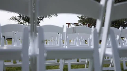 White chairs set up for an outdoor wedding ceremony Stock Footage 338035328