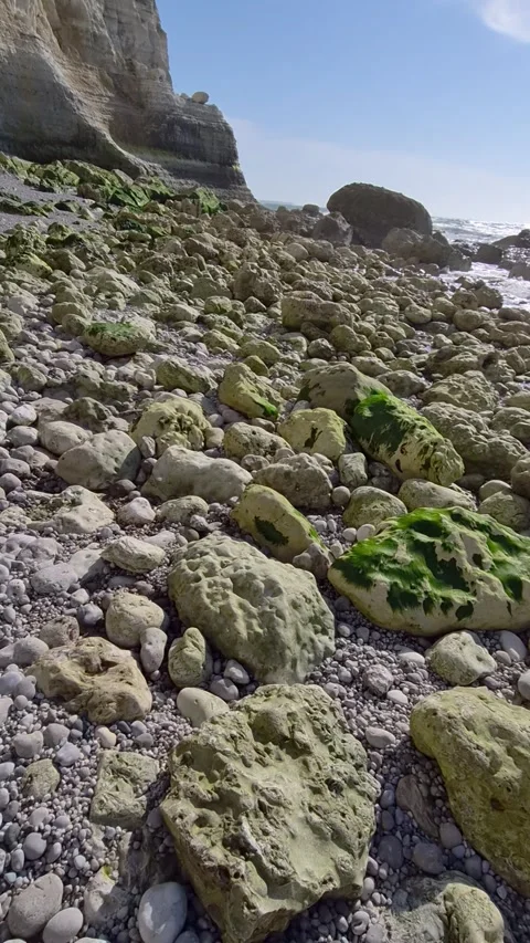 White chalk cliff above a rocky pebble shore near Étretat, Normandy, France 動画素材 346368466