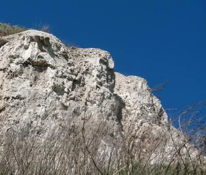 White chalk cliffs with splits on a blue sky basckground Stock Photos