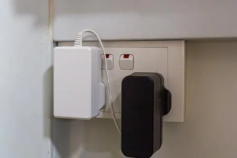 White charger plugged into wall socket Stock Photos