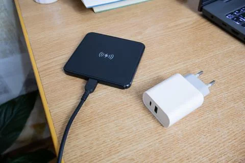White charger using to charge empty battery and black wireless charging pad.. Stock Photos