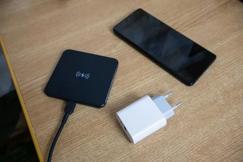 White charger using to charge empty battery, black wireless charging pad an.. Stock Photos