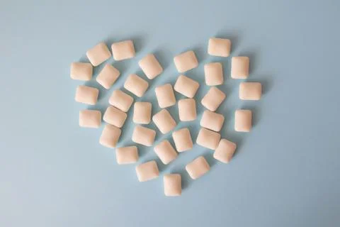 White chewing gums on a blue background laid out in the shape of a heart Stock Photos
