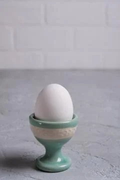 White  chicken  egg in ceramic stand. On a gray concrete background. Foto stock