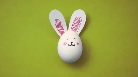 White chicken egg with cute rabbit face and bunny ears on yellow background Stock Footage 292535993