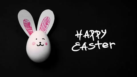 White chicken egg with paper rabbit ears and cute bunny face on black background Stock Footage 331661324