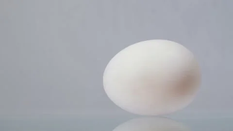 White chicken egg spinning around and rolling on a white background with Stock-Footage 147415054