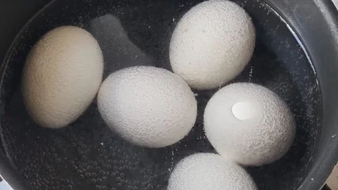 White chicken eggs are boiling in a black pot in the water Stock Footage 335124112