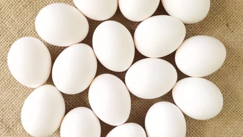 White chicken eggs rotating slowly on a rustic burlap background Stock Footage 339366979