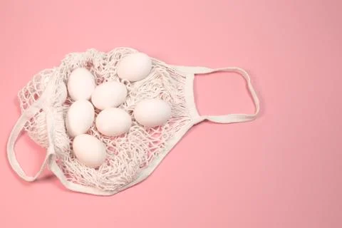 White chicken eggs in a string bag, on a pink background Stock Photos