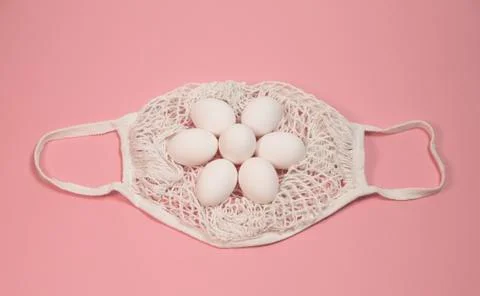 White chicken eggs in a string bag, on a pink background Stock Photos