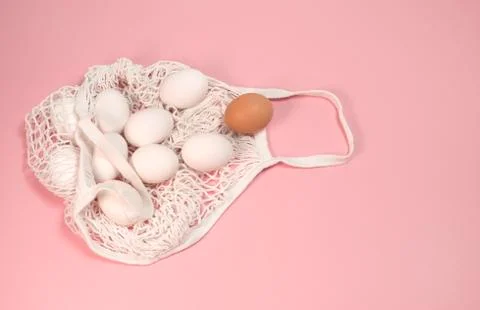 White chicken eggs in a string bag, on a pink background Stock Photos