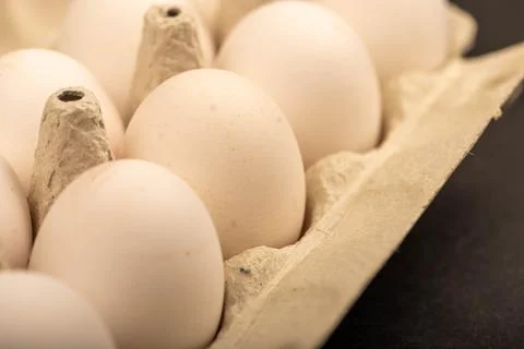 White chicken eggs in a tray made of white cardboard, close-up selective focu Stock Photos
