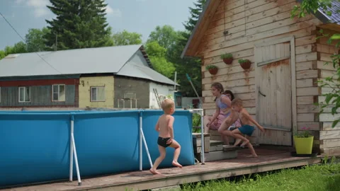 White Children Running And Leaping Into Blue Aboveground Pool From Wooden Deck Stock Footage 330890275