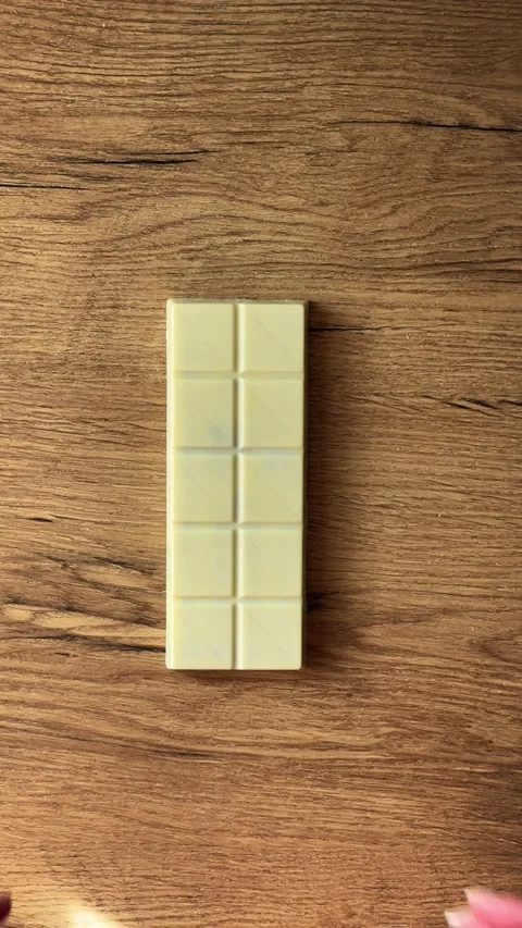 White chocolate bar getting broken by female hands on a wooden table. Delic.. Stock Footage 330956164
