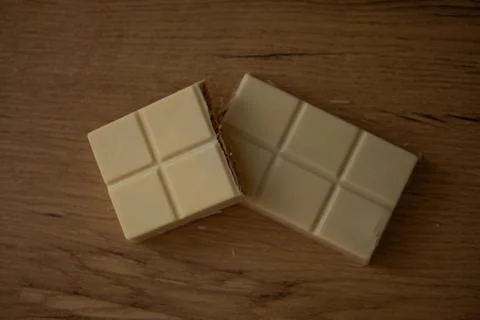 White chocolate bar split in two pieces, displaying the creamy texture and .. Stock Photos