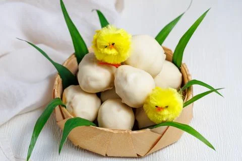 White chocolate easter eggs. Sweet candy eggs in nest on white table with yellow Stock Photos
