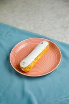 White Chocolate Eclair served in plate isolated on napkin side view of cafe.. Stock Photos