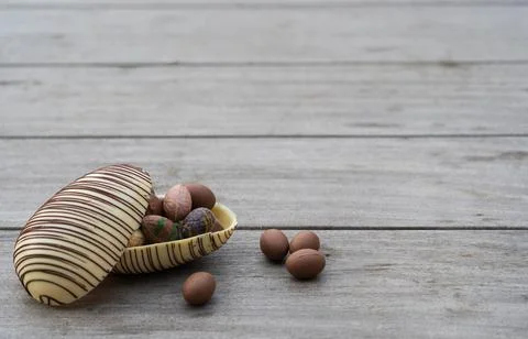 White chocolate egg with dark lines and inside a bunch of small eggs on a r.. Stock Photos