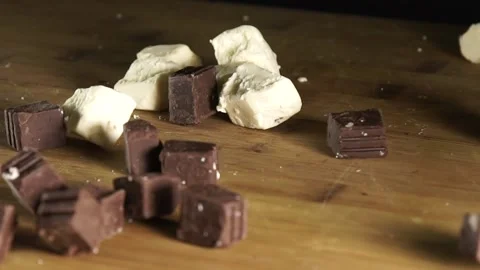 White Chocolates and Dark Chocolates Free Fall on Wooden Chopping Board Stock Footage 201237027