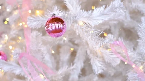 A white Christmas tree with pink ornaments hanging from it Stock Footage 295099201