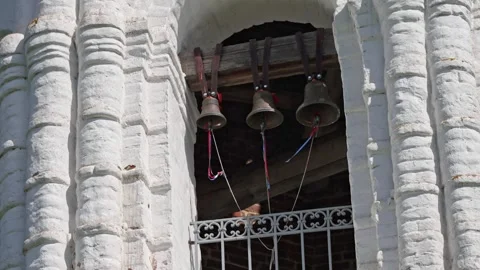 White church bell tower with three bronze bells ringing Stock Footage 344240481
